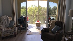 Un salon doté d’une porte-fenêtre coulissante donnant sur un balcon. On y trouve deux canapés, une petite table et une lampe.