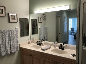 Un baño con dos lavabos, un espejo grande y cuadros en la pared.