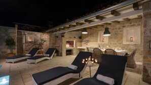 A stone-walled outdoor lounge area with reclining chairs and a dining table. - Holiday Home in Murvica with Seaview, Terrace, Air condition, WIFI (3756-1) (Murvica)