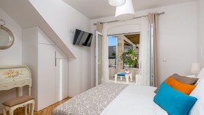 A bedroom with a bed, a desk, a chair, a television, and a balcony with a table and chairs. - Holiday Home in Murvica with Seaview, Terrace, Air condition, WIFI (3756-1) (Murvica)