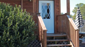 A wooden cabin with a sign reading "HERON'S NEST" and a small porch with steps leading to a door.