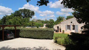 A stone house with a gravel driveway, a parked car, and a well-maintained hedge. - La Réserve, 2/4 person duplex gite, 9x4 pool, Saintes / Royan / Oléron axis (Luchat)