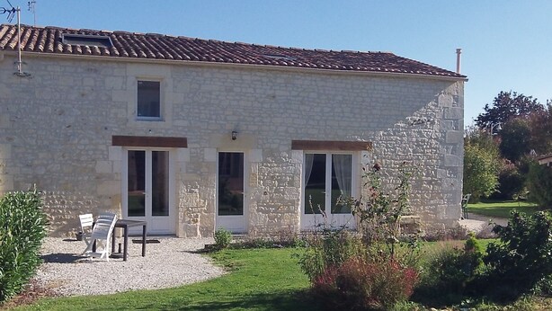 A stone building with a tiled roof, two windows, and a small garden area with a bench and plants. - La Réserve, 2/4 person duplex gite, 9x4 pool, Saintes / Royan / Oléron axis (Luchat)
