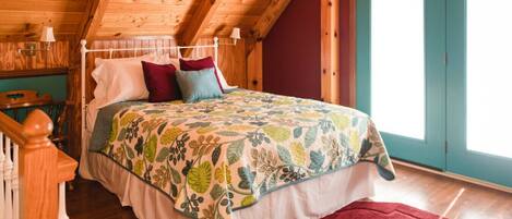 Un dormitorio de cabaña de madera con una cama, un tapete rojo y una escalera de madera.