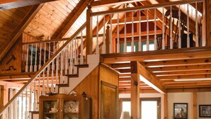 A wooden staircase with white balusters leading to a second floor. A wooden cabinet with glass doors is visible on the first floor.