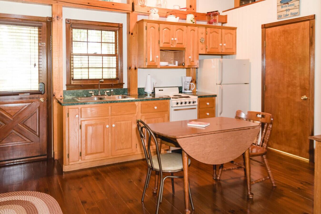 Una cocina con armarios de madera, una estufa, un refrigerador y una mesa de comedor con sillas.