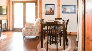 A wooden interior with a dining table, chairs, a sofa, and two framed pictures on the wall.