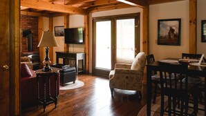 A cozy living room with a fireplace, a television, and a dining area with a table and chairs.