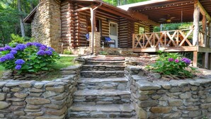 Eine Blockhütte mit einer Steintreppe, die zu einer Holzterrasse führt.