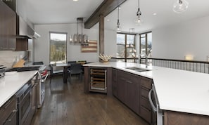 A modern kitchen with a large island, stainless steel appliances, and a view of the outdoors. - Big Sky Vacation Rentals: Homestead 14 Claim Jumper (Big Sky)
