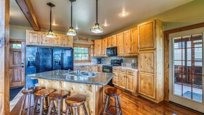A spacious kitchen with wooden cabinets, a granite countertop, and a central island with stools.