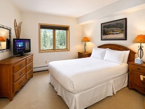 A bedroom with a bed, a dresser, a television, a window, and a painting on the wall. - Walk to River Run • One of Keystone's Largest 4BR/4BA Penthouse (Keystone)