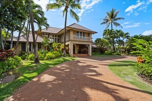 A two-story house with a balcony, surrounded by lush greenery and palm trees. - Luxury, Beachfront- Ka'anapali Beach, Pool & Hot Tub! (Lahaina)