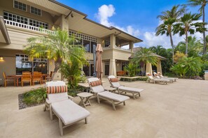 A resort with outdoor seating, palm trees, and a large building with multiple windows.