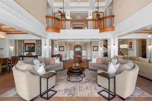 A spacious living area with two sofas, a coffee table, and a staircase leading to an upper level. - Luxury, Beachfront- Ka'anapali Beach, Pool & Hot Tub! (Lahaina)