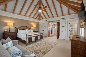 A bedroom with a wooden ceiling, a bed with a headboard, bedside lamps, a nightstand, and a floral-patterned rug. - Luxury, Beachfront- Ka'anapali Beach, Pool & Hot Tub! (Lahaina)