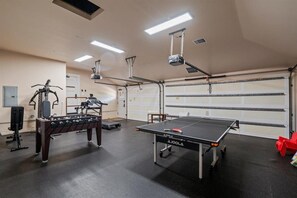 A spacious indoor area with a foosball table, a ping pong table, and exercise equipment. - Luxury, Beachfront- Ka'anapali Beach, Pool & Hot Tub! (Lahaina)