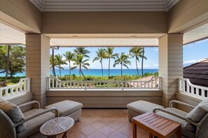 A covered balcony with wicker furniture, a view of the ocean, and palm trees. - Luxury, Beachfront- Ka'anapali Beach, Pool & Hot Tub! (Lahaina)