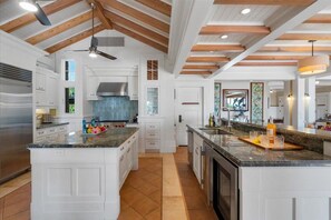 A spacious kitchen with white cabinetry, a large island, and a wooden ceiling. - Luxury, Beachfront- Ka'anapali Beach, Pool & Hot Tub! (Lahaina)