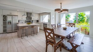 Une cuisine moderne dotée d’un îlot central, de tabourets de bar et d’une table à manger avec des chaises.