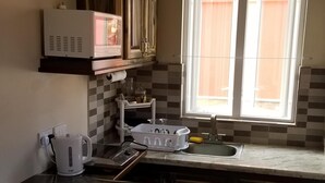 A kitchen with wooden cabinets, a microwave, a kettle, and a window with blinds. - Private 1 bedroom, modern  self contained   cottage in the heart of Soufriere  (Soufriere)