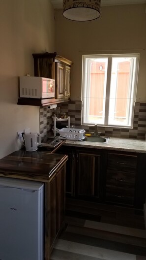 Een koelkast, een magnetron, een waterkoker, kookgerei, borden en bestek