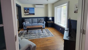 Een woonkamer met een blauwe bank, een kamerbreed tapijt en een houten salontafel.