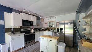 Een moderne keuken met witte kasten, roestvrijstalen apparatuur en een houten aanrecht.