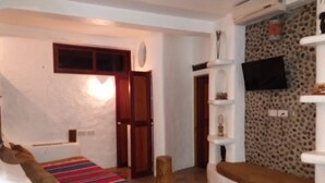 Un salon avec un canapé, un téléviseur fixé au mur, un mur à motifs et une porte.