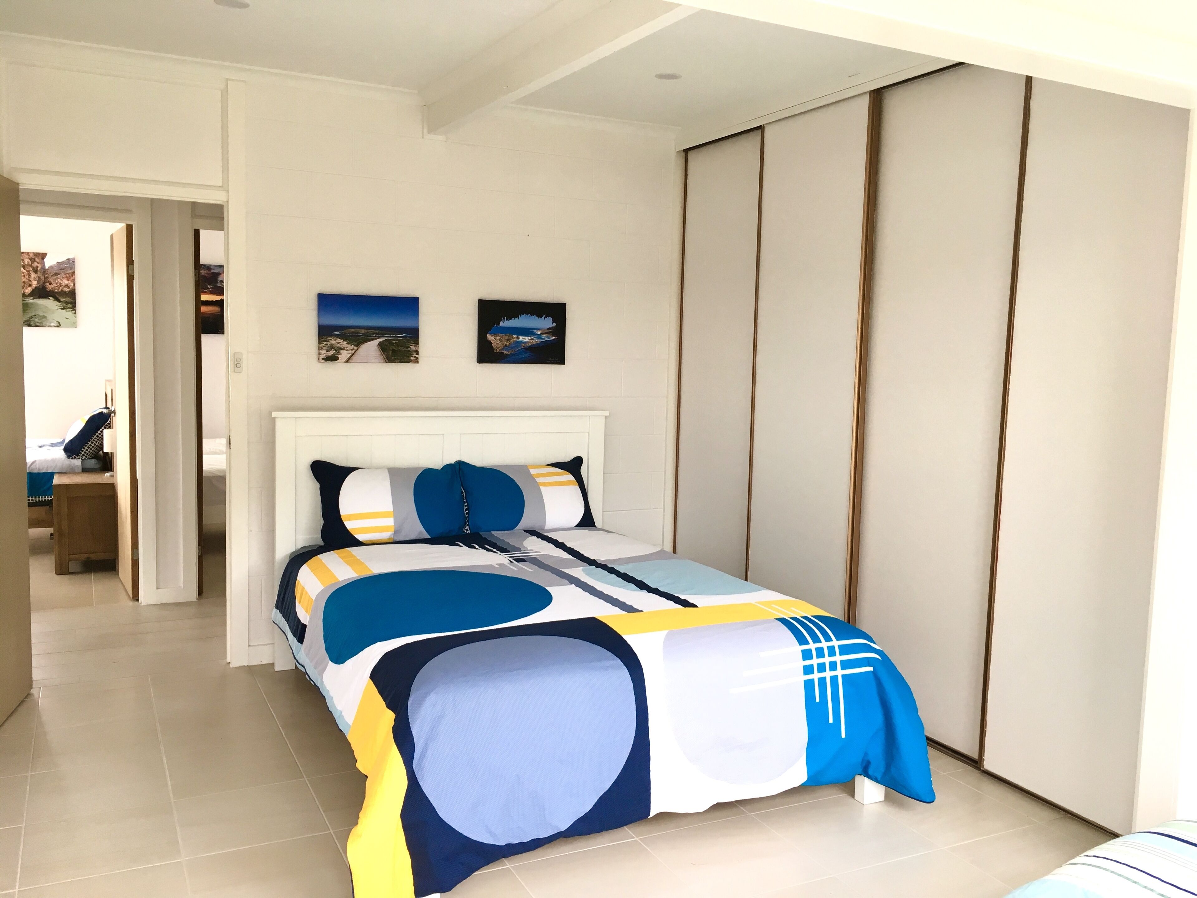 Quarto com cama, guarda-roupa e duas molduras na parede.