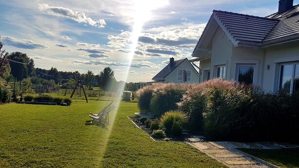 Una propietat residencial amb un jardí ben cuidat, un camí que porta a la casa i un cel serè.