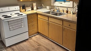 A kitchen with wooden cabinets, a white stove, a sink, and a microwave.