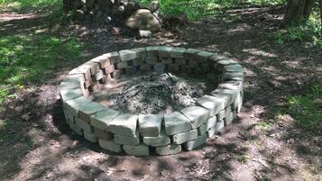 A circular fire pit made of bricks in a forested area.