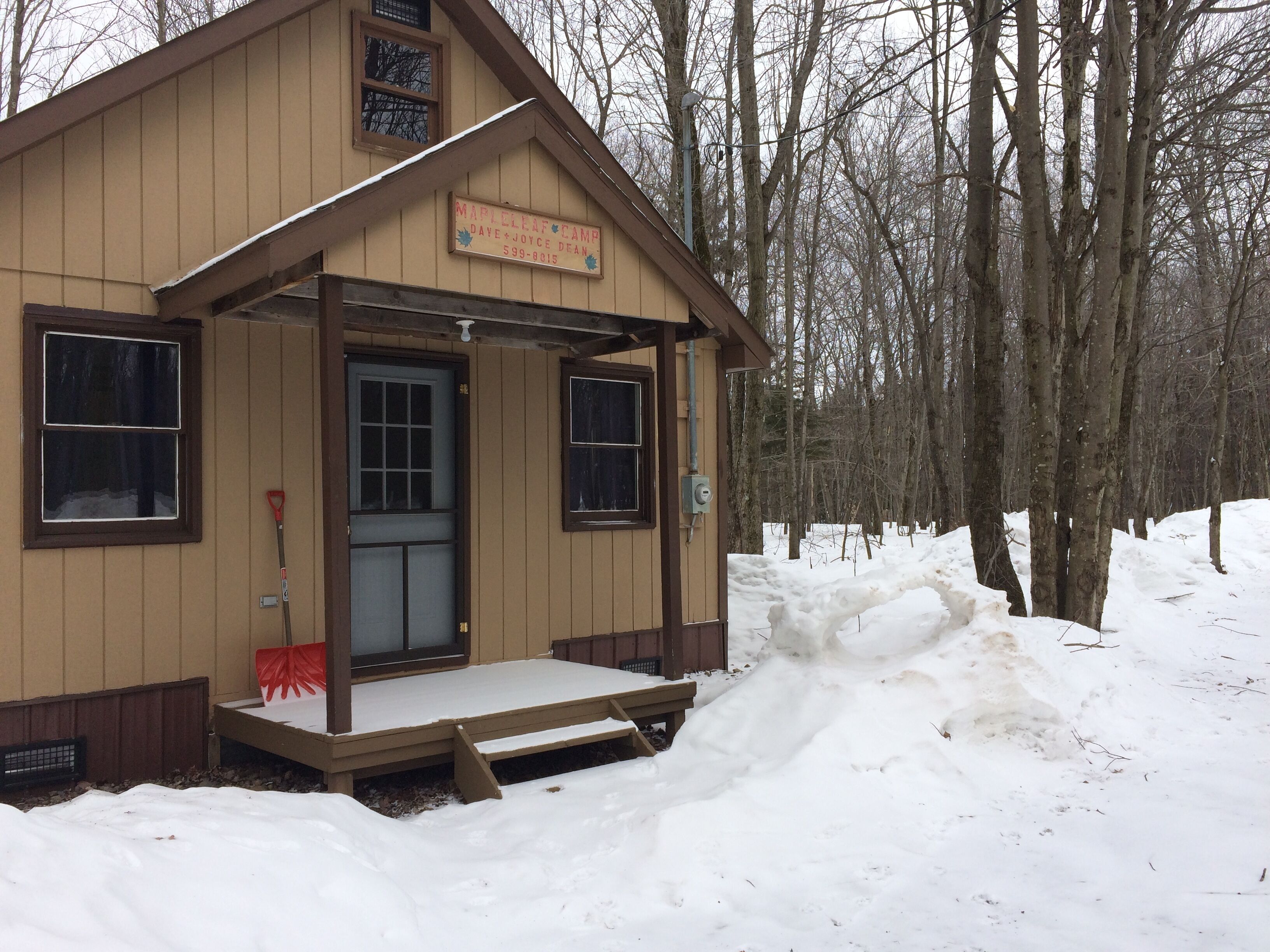 Une petite cabane en bois avec une pancarte indiquant « Camp Maple Leaf » et les coordonnées.