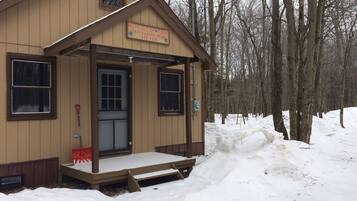 Une petite cabane en bois avec une pancarte indiquant « Camp Maple Leaf » et les coordonnées.