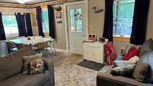 A cozy living room with a dining area, a white door, and a view of the outdoors.