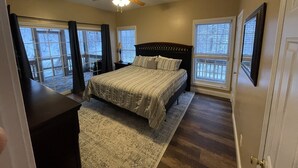 Un dormitorio con cama, ventilador de techo, ventana y puerta.