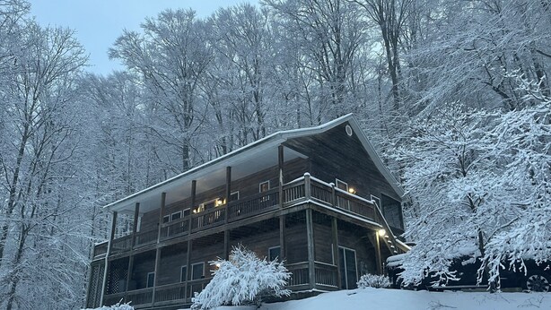 Una cabaña de madera con varios balcones, rodeada de árboles cubiertos de nieve.