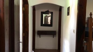 A hallway with a tiled floor, wooden doors, a hanging light fixture, and a wall-mounted mirror. - BEAUTIFUL COTTAGE WITH POOL AND LAKE (EXTREMA)
