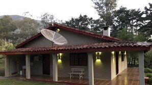 A house with a tiled roof, a satellite dish, and a covered porch with a bench. - BEAUTIFUL COTTAGE WITH POOL AND LAKE (EXTREMA)