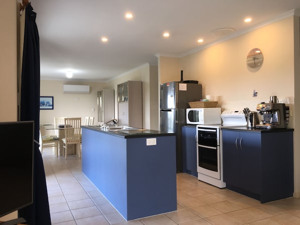A modern kitchen with a central island, built-in appliances, and a dining area with chairs.
