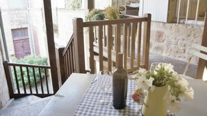 Ett bord med en flaska och ett glas, en stol och en utsikt över en byggnad i sten.
