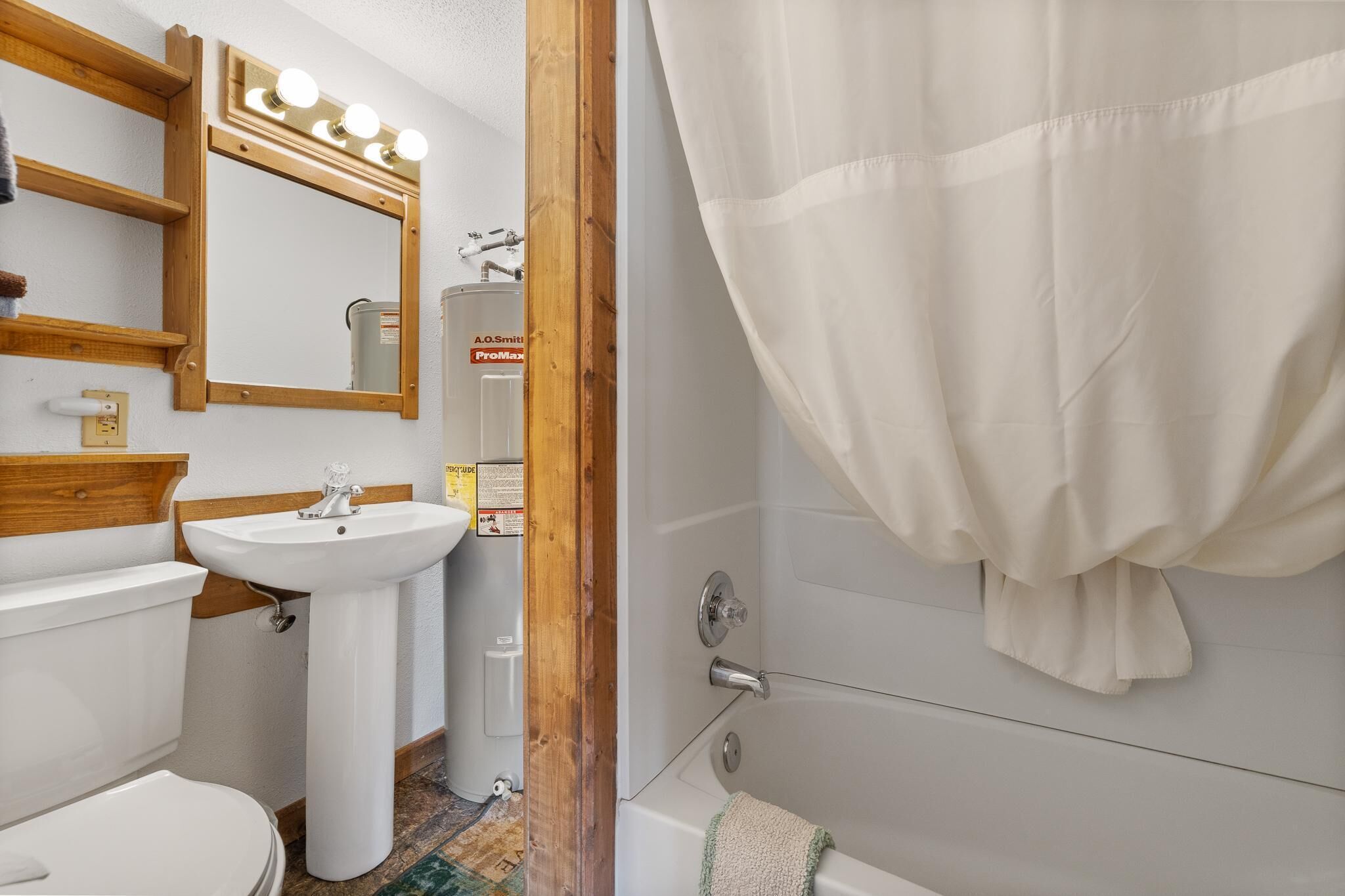 A bathroom with a sink, mirror, vanity, and shower curtain.