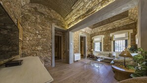 A spacious living room with stone walls, a wooden floor, and a sofa set. - Marim Villas - Villa Flamingo  (Olhão)