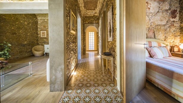 A narrow hallway with stone walls, a tiled floor, and a bed with striped bedding. - Marim Villas - Villa Flamingo  (Olhão)