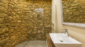 A bathroom with a stone wall, a white sink, and a mirror. - Marim Villas - Villa Flamingo  (Olhão)