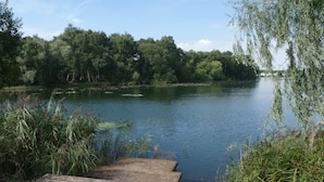 A wooden dock extending into a calm river surrounded by dense greenery.
