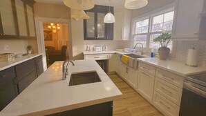 A modern kitchen with a central island, white cabinetry, a large window, and pendant lighting.