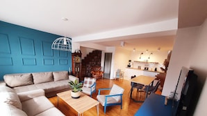 A modern living room with a sofa, a coffee table with a plant, and a dining area with chairs and a table. - Duplex 150m2 - Central Station best location in town (Skopje)
