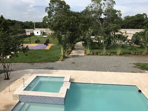 Relax by the pool surrounded by lush greenery and a nearby jacuzzi.